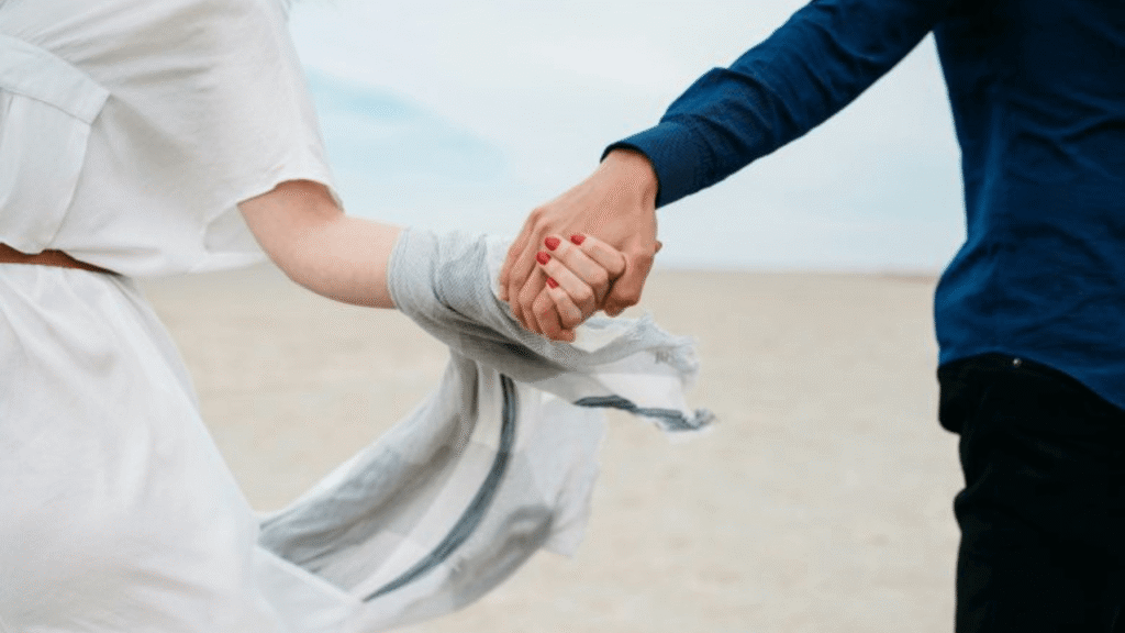 couple holding hands while walking on a beach, symbolizing  and appreciating meaningful relationships in the present moment.